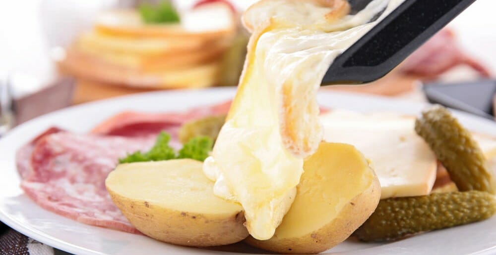 Assiette de raclette avec pommes de terre, fromage fondu, charcuterie et cornichons pour conseils sur comment digérer la raclette