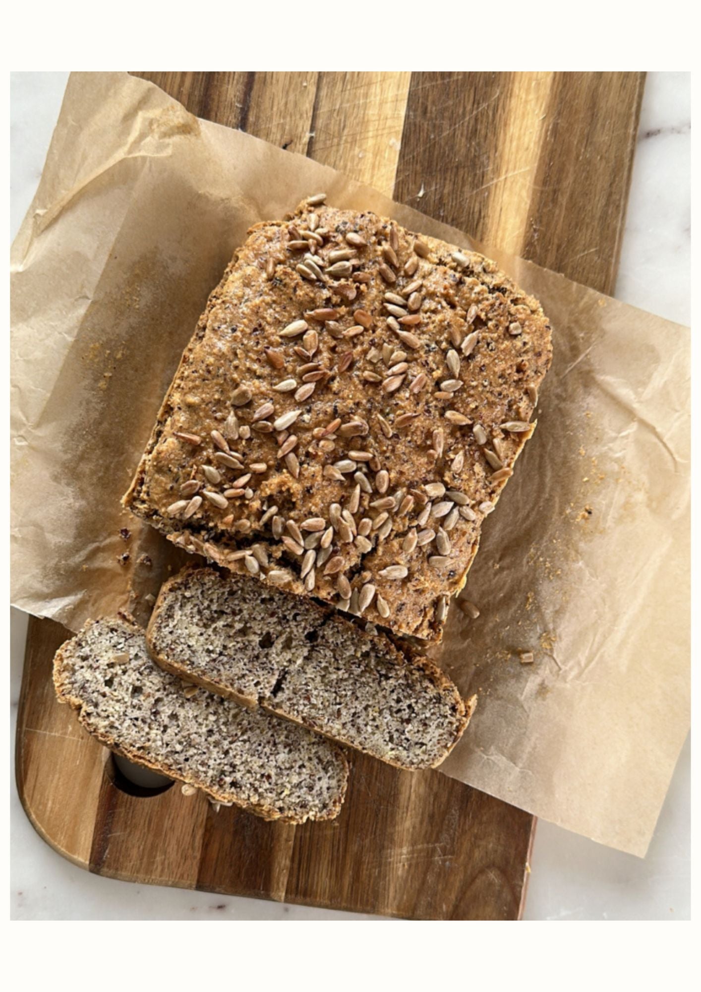 Pain de mie maison Low FODMAP garni de graines sur une planche en bois avec une tranche coupée