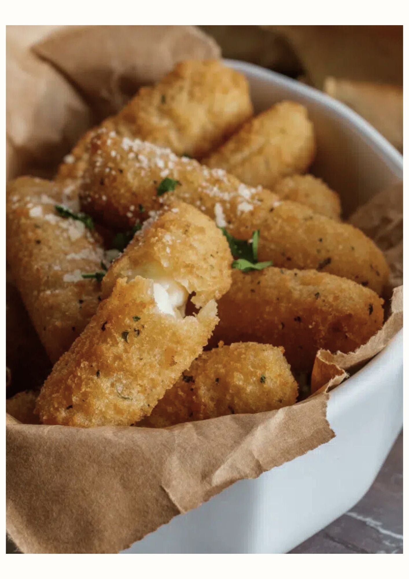 Sticks de mozzarella croustillants dans un plat, garnis d'herbes et de fromage râpé