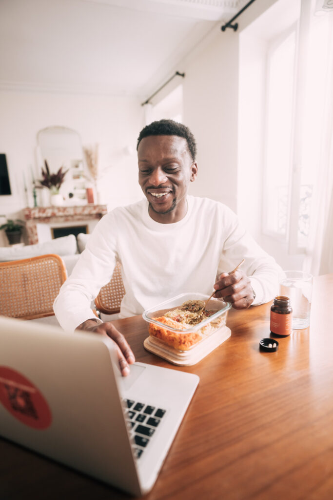 Homme utilisant un ordinateur portable à la maison en consultant l'annuaire gastro-entérologues tout en mangeant un repas sain