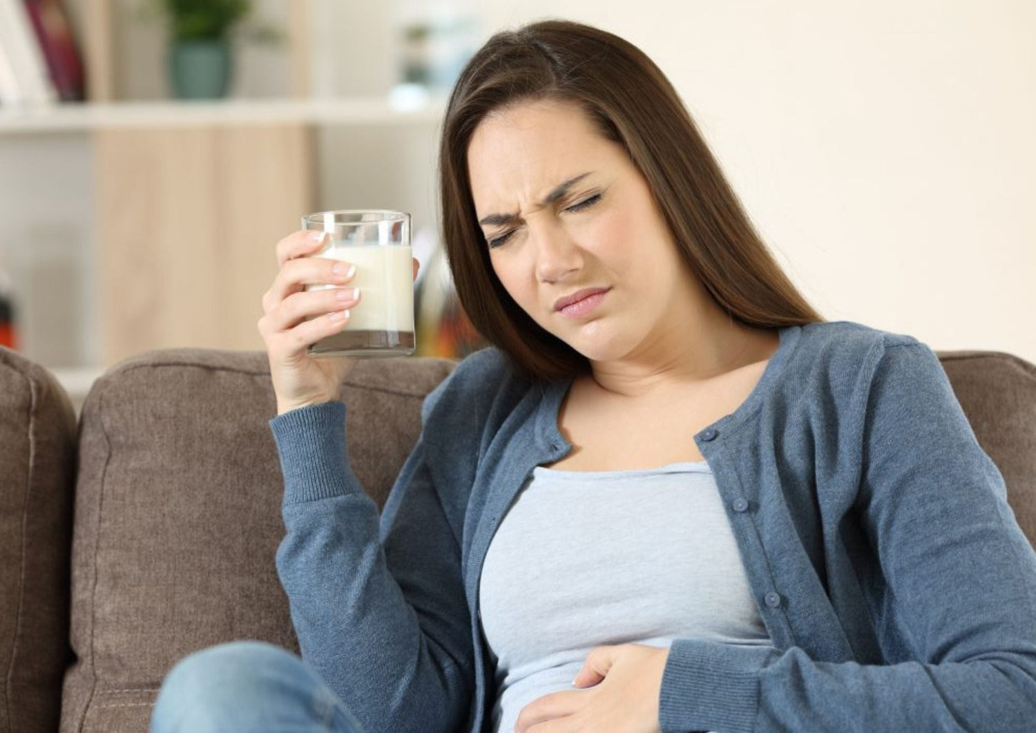 Femme souffrant de douleurs abdominales après avoir consommé un produit laitier, illustrant les intolérances et digestion
