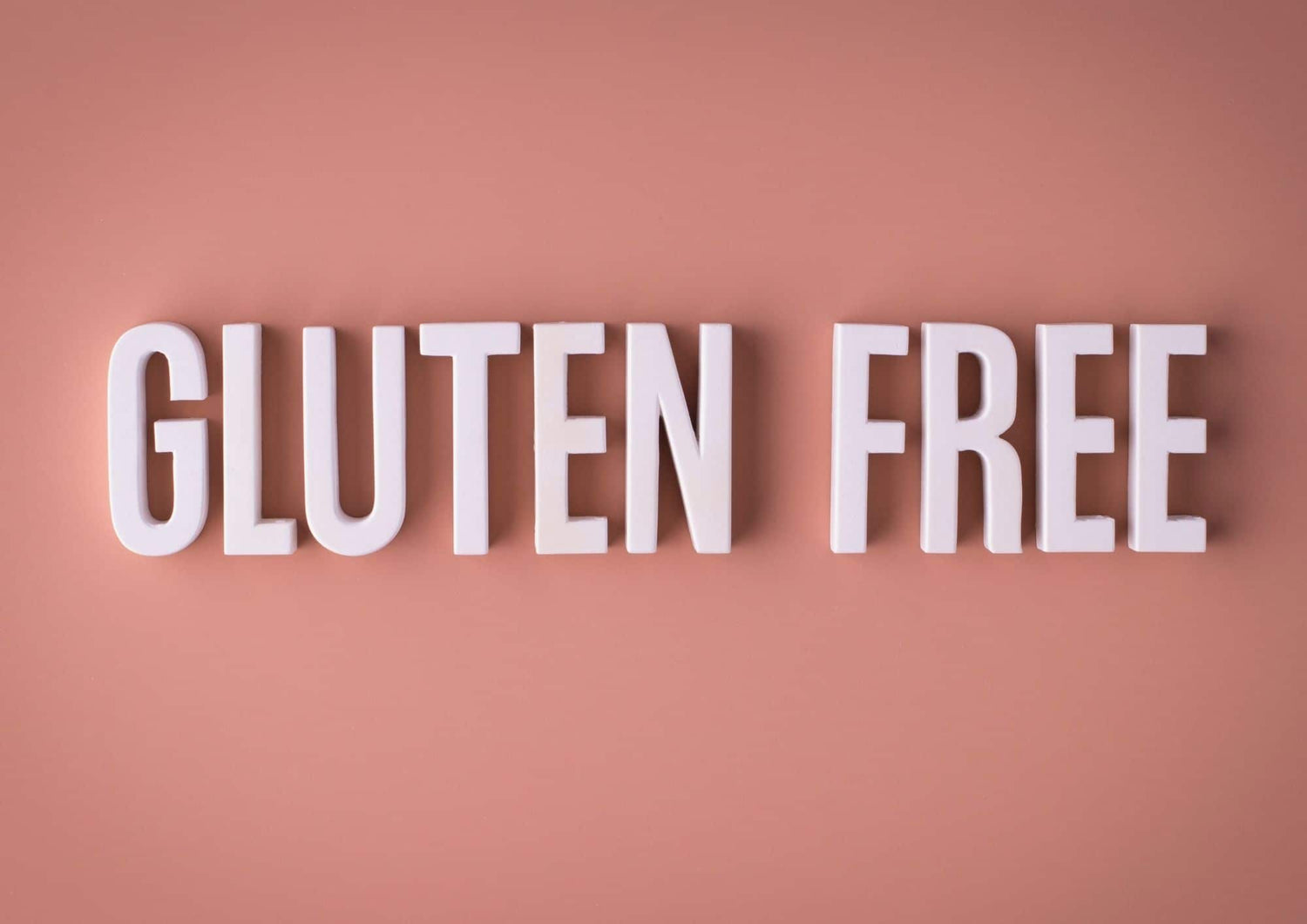 Texte gluten free en lettres blanches sur fond rose illustrant la prise en charge alimentation sans gluten