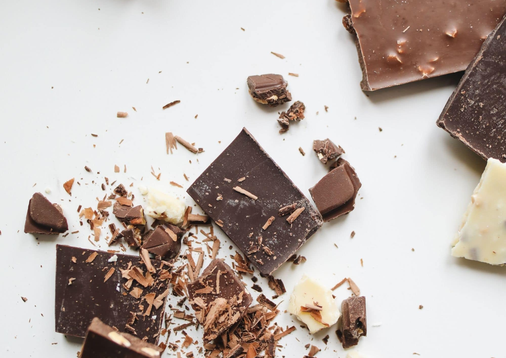 Morceaux de chocolat noir et chocolat blanc éparpillés sur fond blanc pour chocolat noir et intestin irritable