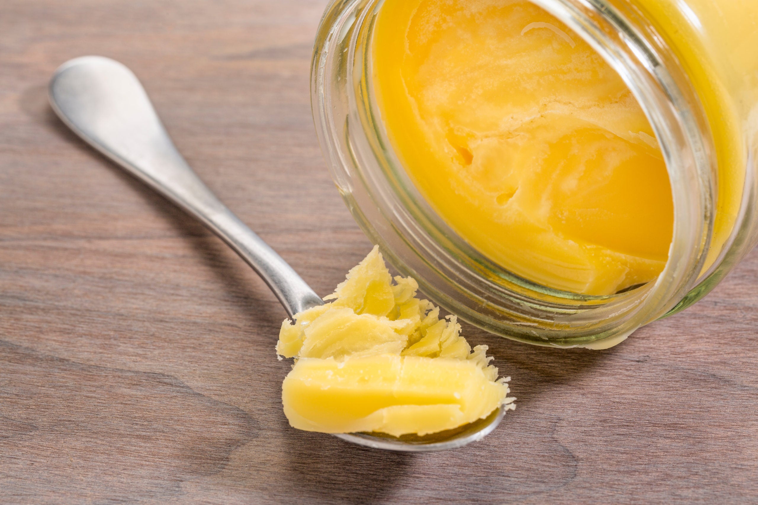 Pot de beurre ghee avec une cuillère en métal contenant le beurre clarifié doré