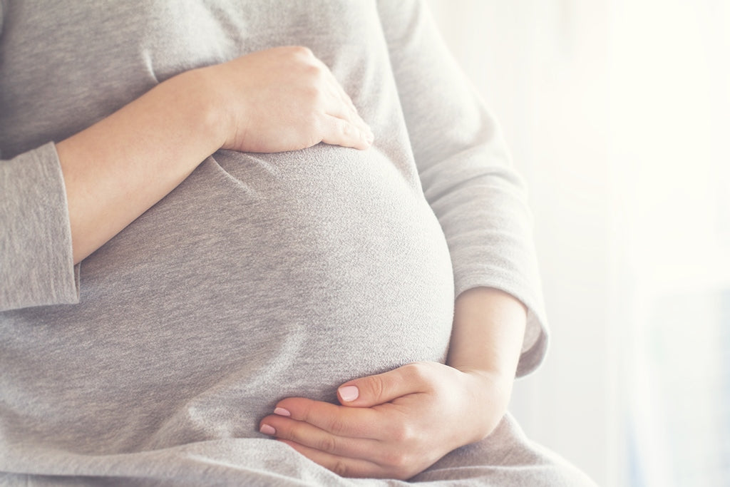 Femme enceinte tenant son ventre, abordant le thème de la grossesse et troubles digestifs