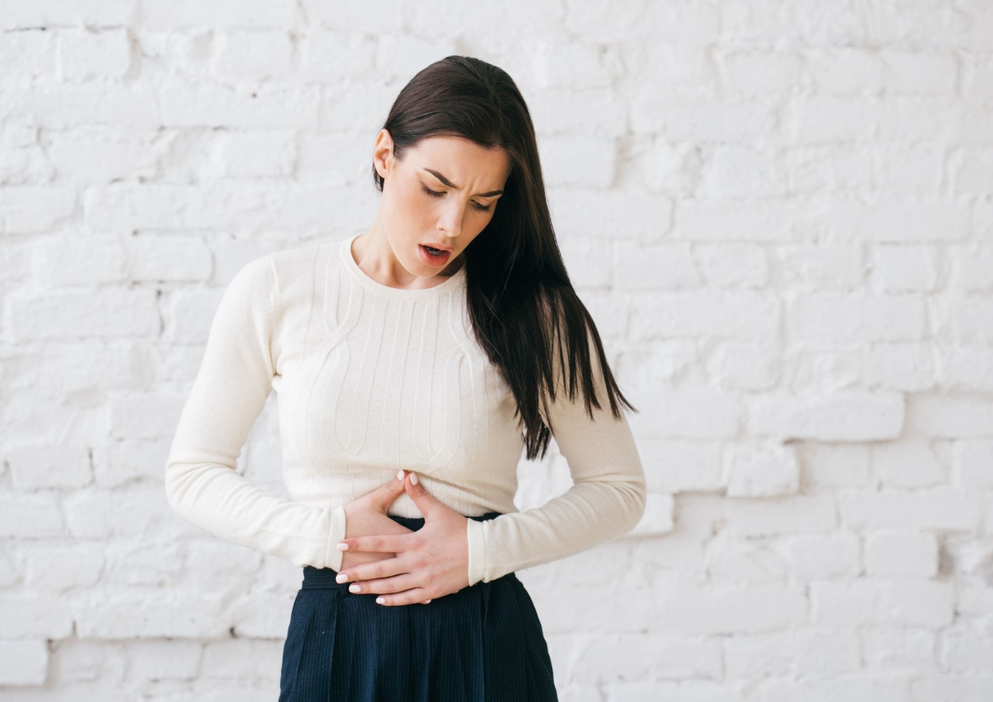 Femme tenant son ventre en raison de douleurs liées à l'inflammation des intestins : tout comprendre