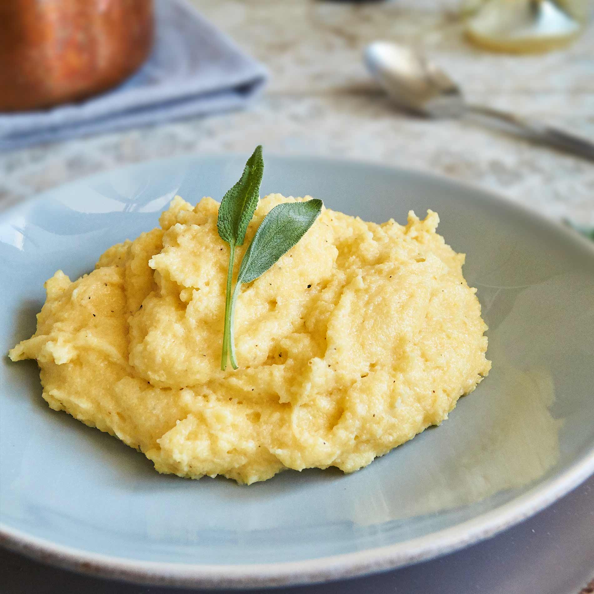 Polenta crémeuse garnie de feuilles de sauge, idéale pour apprendre comment cuisiner la polenta